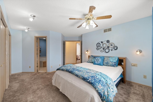 carpeted bedroom with visible vents, a ceiling fan, a textured ceiling, ensuite bath, and baseboards