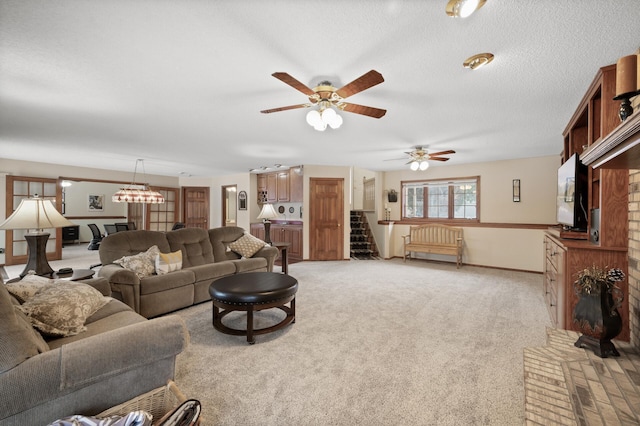 living area with ceiling fan with notable chandelier, a textured ceiling, stairway, baseboards, and light colored carpet