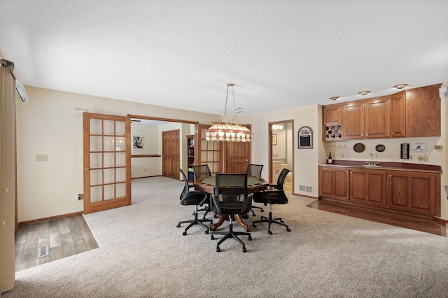 dining room with a textured ceiling, baseboards, visible vents, and light carpet