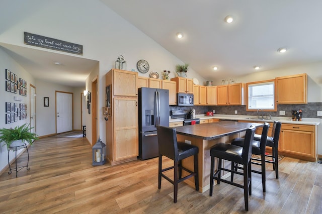 kitchen featuring backsplash, a center island, a kitchen bar, sink, and appliances with stainless steel finishes