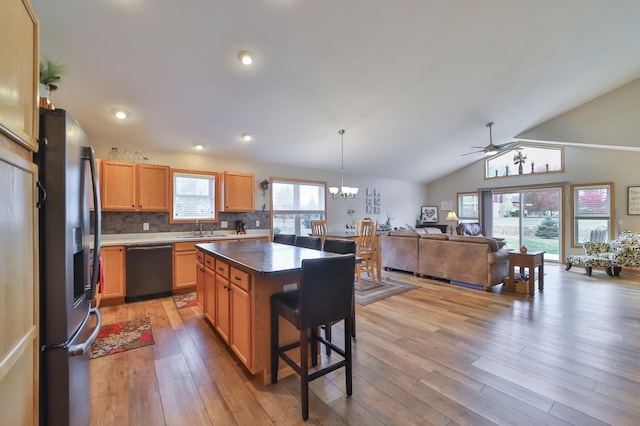 kitchen featuring backsplash, dishwasher, a kitchen island, stainless steel fridge, and ceiling fan with notable chandelier