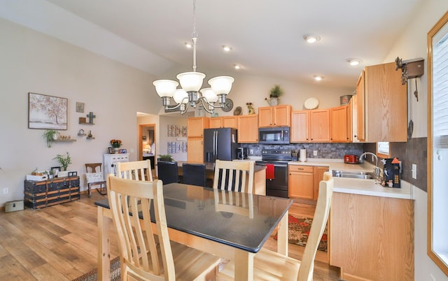 dining area featuring lofted ceiling, sink, a chandelier, and light wood-type flooring