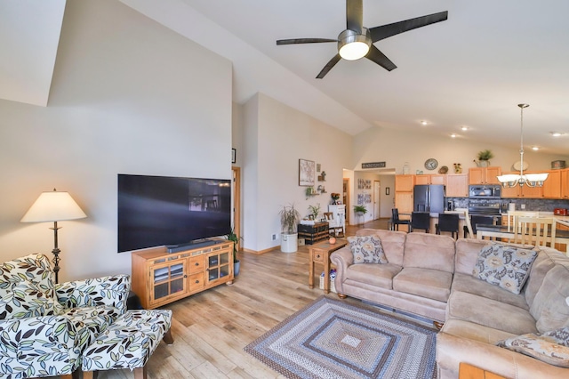 living room with lofted ceiling, ceiling fan with notable chandelier, and light hardwood / wood-style floors