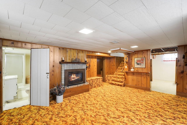 4312 Georgia Ave N, Crystal, MN 55428 - unfurnished living room featuring carpet flooring, a fireplace, stairs, and wooden walls