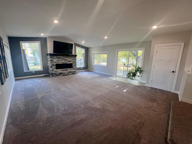 unfurnished living room with a fireplace, plenty of natural light, vaulted ceiling, and carpet flooring