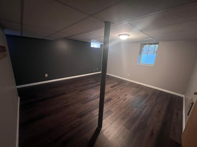 basement featuring a drop ceiling and dark wood-type flooring