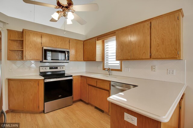 kitchen with light hardwood / wood-style floors, tasteful backsplash, sink, stainless steel appliances, and kitchen peninsula