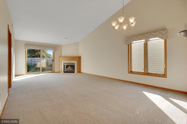 unfurnished living room with high vaulted ceiling, a notable chandelier, and carpet floors