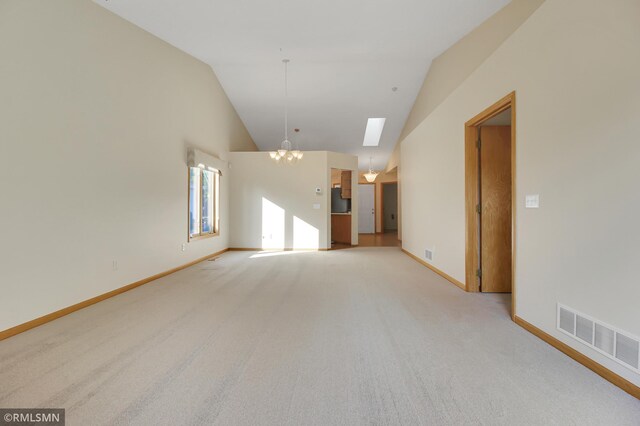 unfurnished room with light carpet, a notable chandelier, and vaulted ceiling with skylight