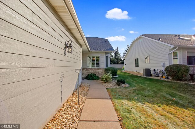 view of home's exterior with cooling unit and a lawn