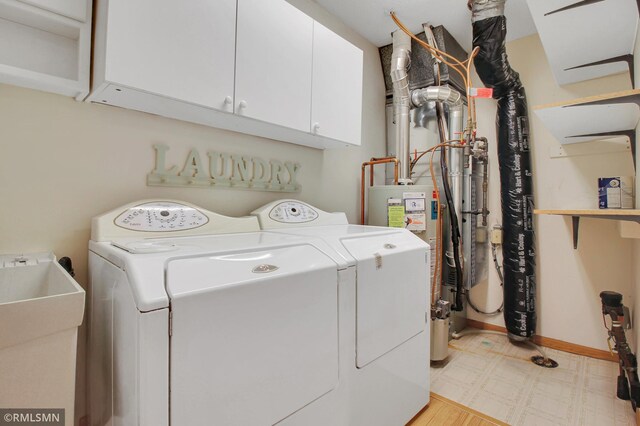 washroom with cabinets, sink, and washing machine and dryer