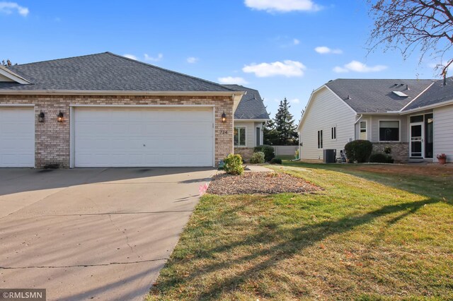 view of front of home with cooling unit, a front yard, and a garage