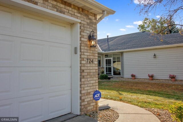 view of exterior entry with a garage and a lawn