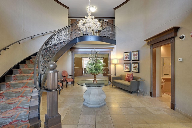 entrance foyer featuring a high ceiling, a notable chandelier, crown molding, and light tile patterned floors