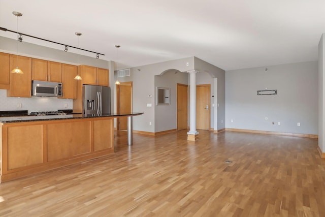 kitchen featuring appliances with stainless steel finishes, decorative columns, pendant lighting, and light hardwood / wood-style floors