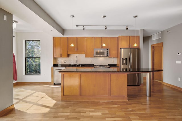 kitchen featuring track lighting, decorative light fixtures, stainless steel appliances, and light hardwood / wood-style flooring