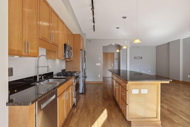 kitchen featuring a kitchen island, sink, light hardwood / wood-style floors, appliances with stainless steel finishes, and decorative light fixtures