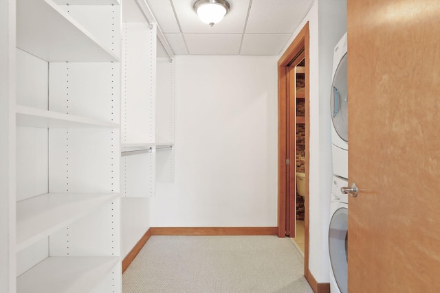 walk in closet with stacked washer and dryer, a drop ceiling, and carpet floors