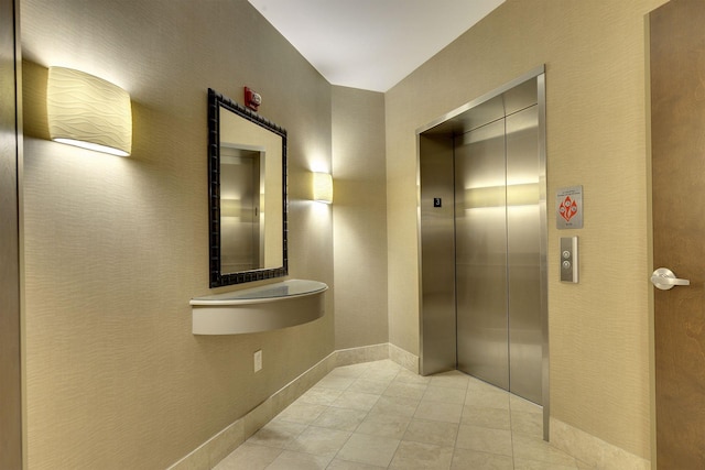 hall featuring elevator and light tile patterned floors