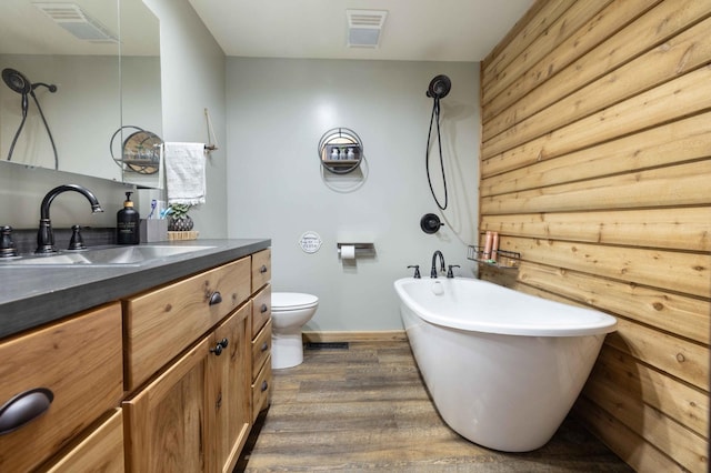 bathroom featuring hardwood / wood-style floors, a tub, vanity, and toilet