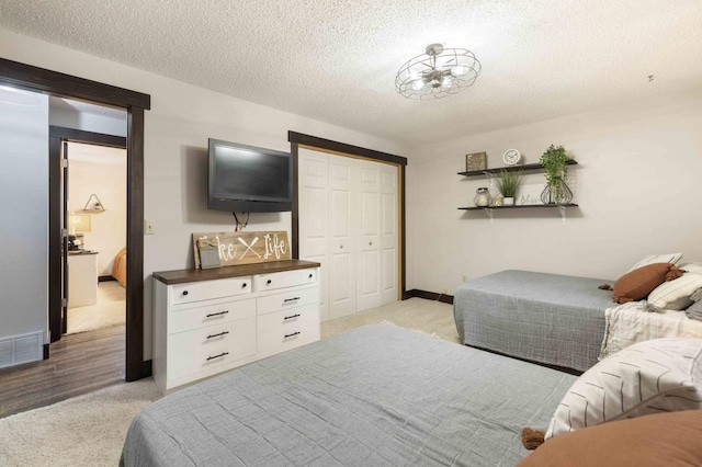 carpeted bedroom with a closet and a textured ceiling