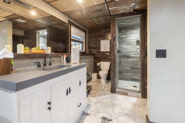 bathroom with vanity, wood walls, toilet, and a shower with door