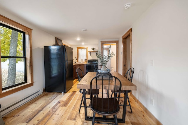 dining space with light hardwood / wood-style floors, a baseboard heating unit, and sink