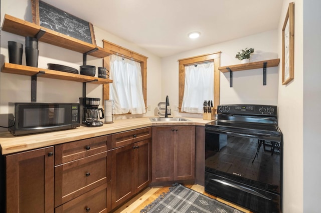 kitchen with butcher block countertops, dark brown cabinets, black appliances, and sink