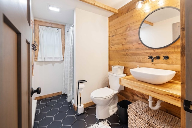 bathroom with wooden walls, walk in shower, sink, tile patterned flooring, and toilet