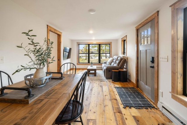 dining space with light hardwood / wood-style flooring and a baseboard radiator