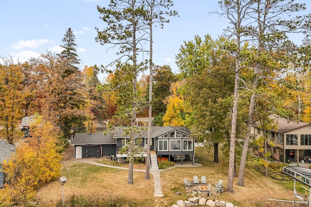 rear view of property with an outdoor fire pit, a sunroom, and a deck