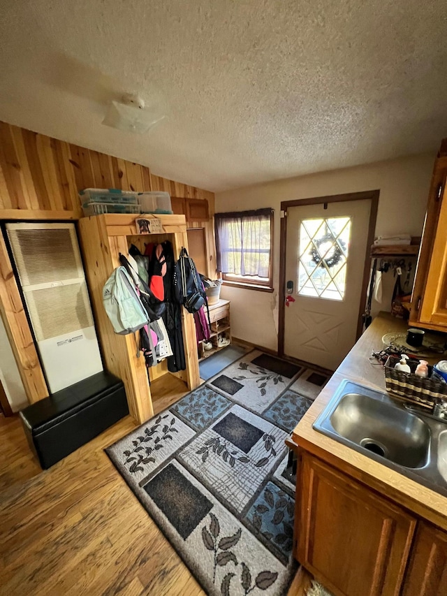 mudroom with lofted ceiling, wood-type flooring, sink, wood walls, and a textured ceiling