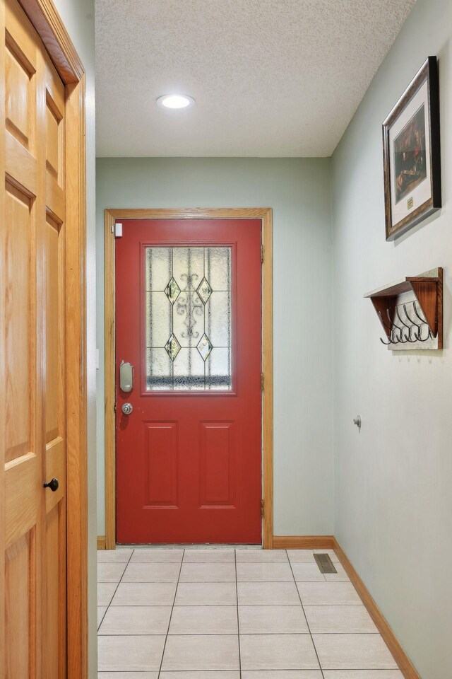 doorway with a textured ceiling and light tile patterned floors