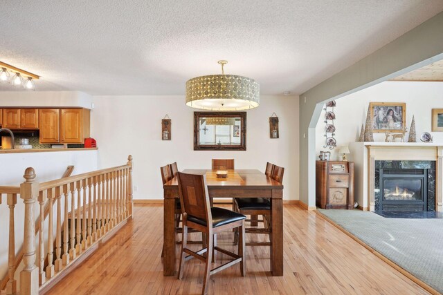 dining space with a premium fireplace, light hardwood / wood-style flooring, and a textured ceiling