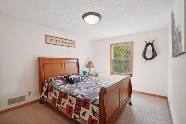 bedroom featuring light colored carpet and a textured ceiling