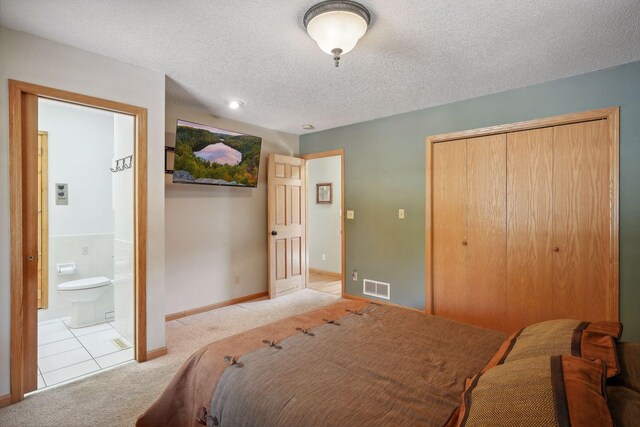 bedroom with light carpet, a textured ceiling, a closet, and connected bathroom