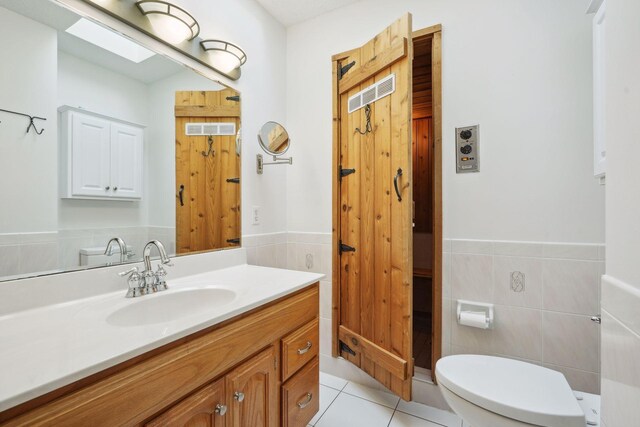 bathroom with vanity, tile walls, toilet, and tile patterned floors