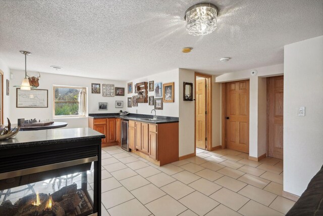 kitchen featuring beverage cooler, sink, light tile patterned flooring, decorative light fixtures, and a textured ceiling