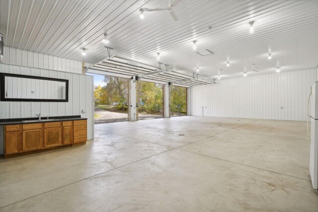 garage featuring white fridge, ceiling fan, and sink