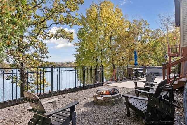 view of patio with a fire pit and a deck with water view