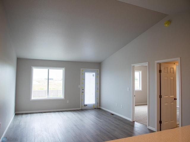 spare room with plenty of natural light, dark wood-type flooring, and vaulted ceiling