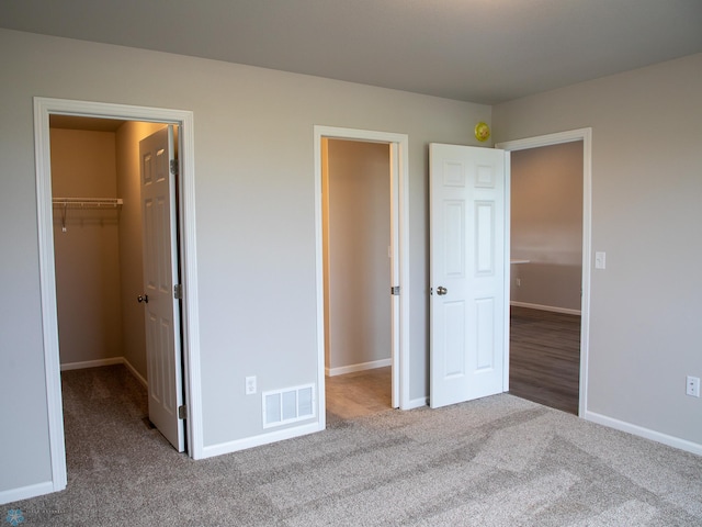 unfurnished bedroom with light colored carpet, a spacious closet, and a closet