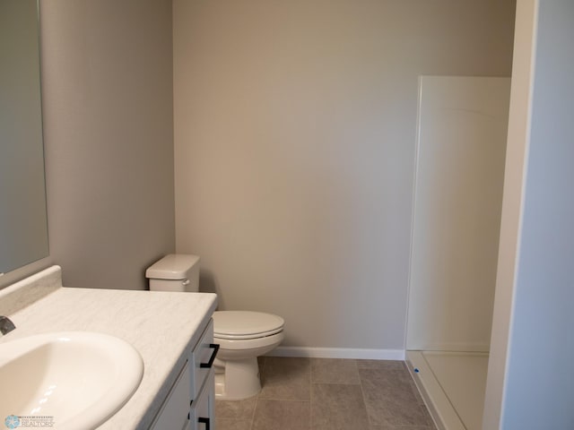 bathroom featuring tile patterned flooring, vanity, toilet, and walk in shower