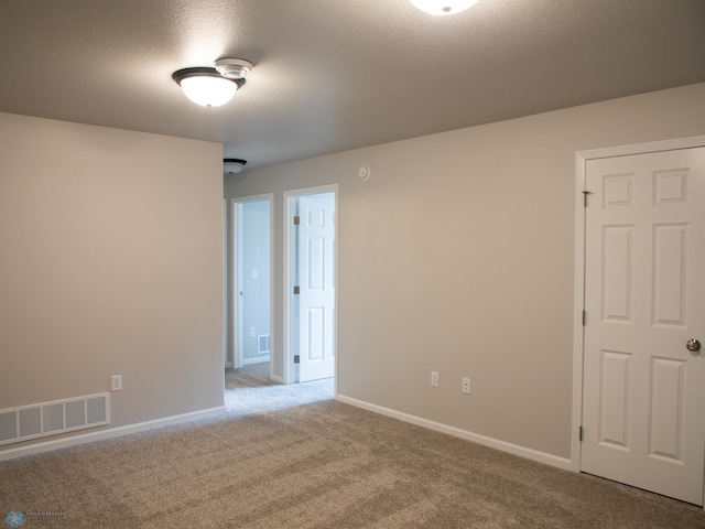 carpeted empty room featuring a textured ceiling