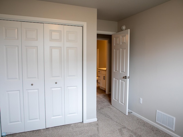 unfurnished bedroom featuring light colored carpet and a closet