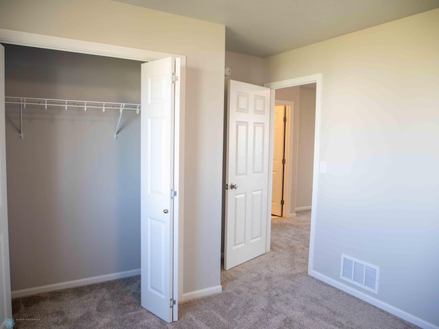 unfurnished bedroom featuring light colored carpet and a closet