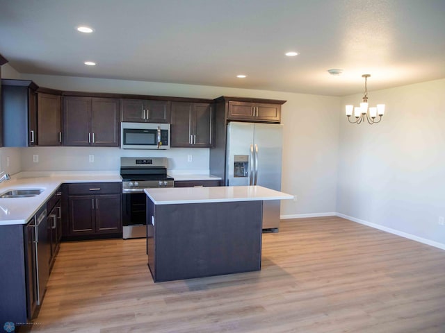 kitchen with stainless steel appliances, pendant lighting, a chandelier, light hardwood / wood-style floors, and a kitchen island