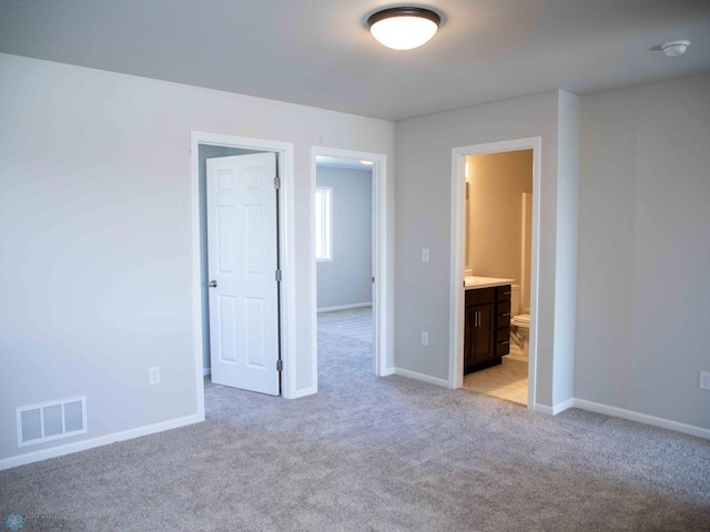 unfurnished bedroom with light carpet and ensuite bath