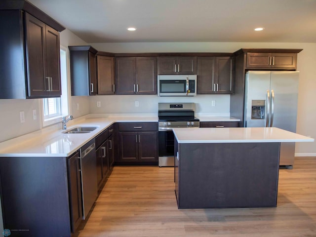 kitchen with a center island, light wood-type flooring, stainless steel appliances, and sink