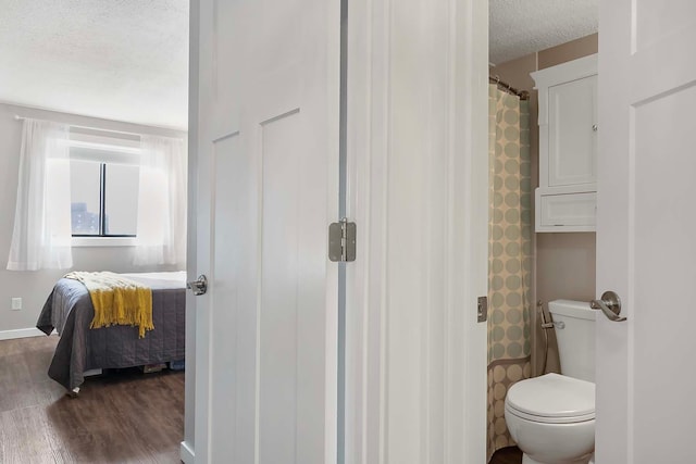 bathroom featuring a textured ceiling, a shower with curtain, hardwood / wood-style flooring, and toilet